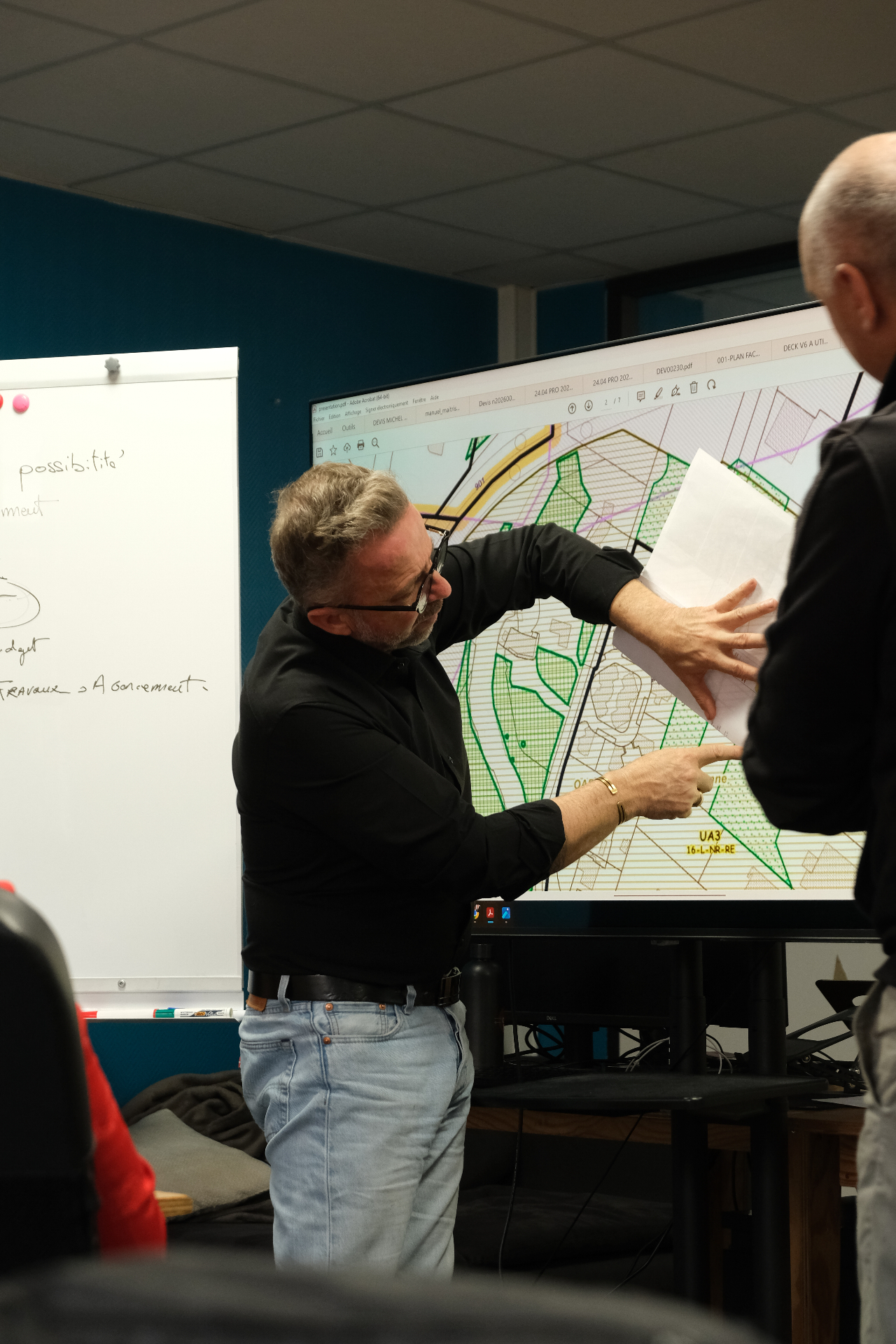 Michel Seixas analysant un plan cadastral avec un client